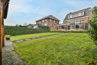 Amsterdam, Hollanda - 10 Nisan 2021: Arka planda çimenlerin, çalıların ve evlerin bulunduğu bir dış alan, güneşli bir günün ardından çekilmiştir.