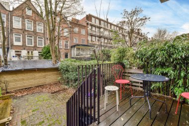 Amsterdam, Hollanda - 10 Nisan 2021: tuğla evlerin önünde yan kaldırımda birkaç masa ve sandalye bulunan bir dış alan