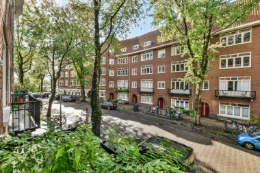 Amsterdam, Hollanda - 10 Nisan 2021: Caddenin her iki tarafında birçok bisiklet ve ağaç park edilmiş bir cadde