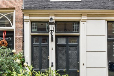 Amsterdam, Hollanda - 10 Nisan 2021: Önünde bitkiler ve evin diğer tarafında açık bir kapı olan bir evin dışı