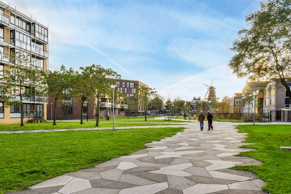 Stock image Amsterdam, Netherlands - 10 April, 2021: a person walking down a path in the middle of an urban area with trees and buildings on either side of it