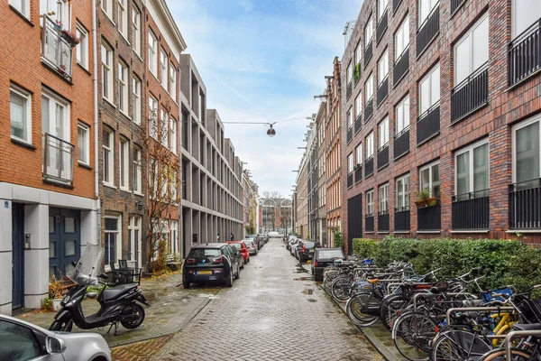 2021年4月10日 荷兰阿姆斯特丹 一些自行车停放在城市地区的一条砖街旁边 街道上有红砖建筑和白窗 — 图库照片