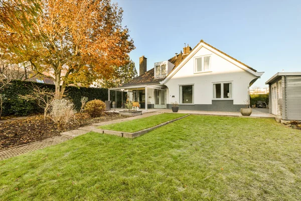 Stock image a house in the fall with an orange tree and green grass on the front yard, surrounded by yellow leaves