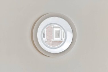 Çemberin üst ve alt kısmında tuğla desenli yuvarlak bir pencere beyaz.