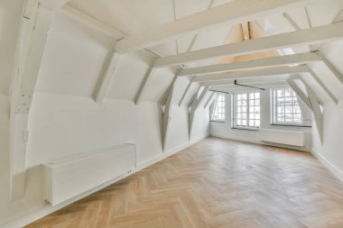 Odanın ortasında beyaz duvarları ve ahşap döşemeleri olan boş bir oda var.