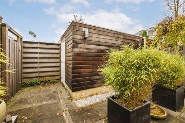 Dışarıda bir yerde, çitlerle çevrili bir arka bahçenin önünde saksılar ve bitkiler var.