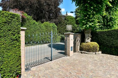 Amsterdam, Hollanda - 10 Nisan 2021: Parlak mavi bir gökyüzü gününde yeşil çalılar ve ağaçlarla çevrili tuğla bir evin ortasındaki bir kapı