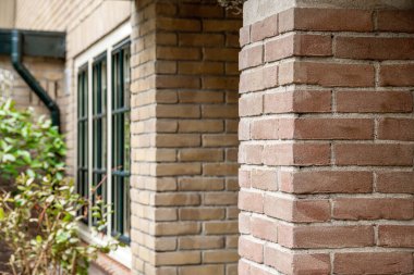 Amsterdam, Hollanda - 10 Nisan 2021: Tuğladan bir bina, yanında bir saat ve arkasında çalılar var.