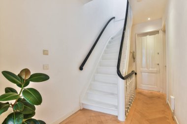 Ahşap döşemeli beyaz bir merdiven ve merdivenlerin kenarında ahşap tırabzanlar var.