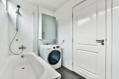 Duvara monte edilmiş kapının yanında çamaşır makinesi ve kurutma makinesi olan bir çamaşır odası.