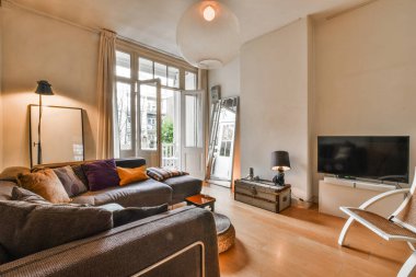 Odanın ortasında kanepeleri ve düz ekran televizyonu olan bir oturma odası duvarda gösteriliyor.