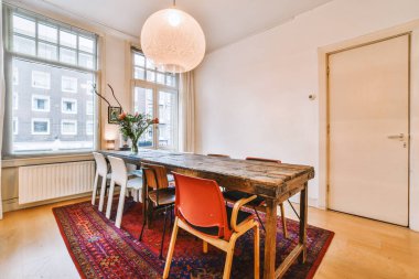 Masası ve sandalyeleri olan büyük bir pencerenin önünde şehir caddesine bakan bir yemek odası.