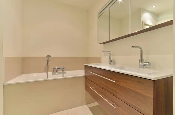 白い壁に現れるのと同じ色の洗面器鏡とバスタブ付きの浴室です — ストック写真