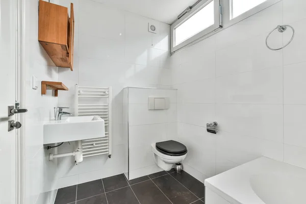 Bílá Koupelna Černou Dlaždicovou Podlahou Dřevěnou Skříňkou Toaleta Rohu Vedle — Stock fotografie