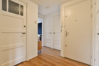 Kapının her iki tarafında beyaz kapılı ve ahşap döşemeli boş bir oda, başka bir odaya bakıyor.