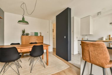 Beyaz duvarları, ahşap döşemeleri ve yerde halı olan bir odada yemek masası ve sandalyeler.