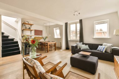 Odanın ortasında kanepeleri, sandalyeleri ve sehpası olan bir oturma odası beyaz duvarlarla dolu.