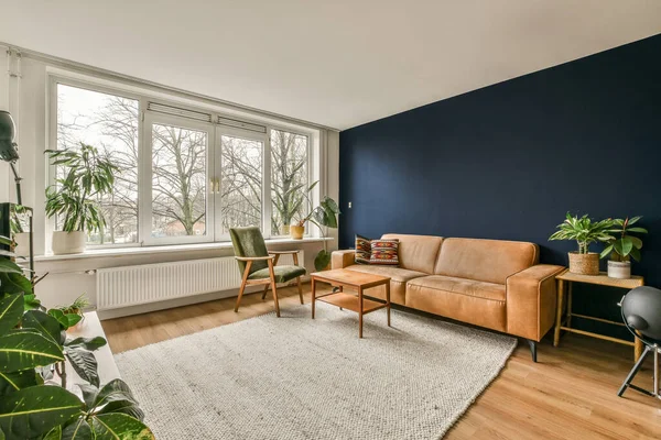 大きな窓の前にソファと椅子と植物のあるリビングルームがあり — ストック写真