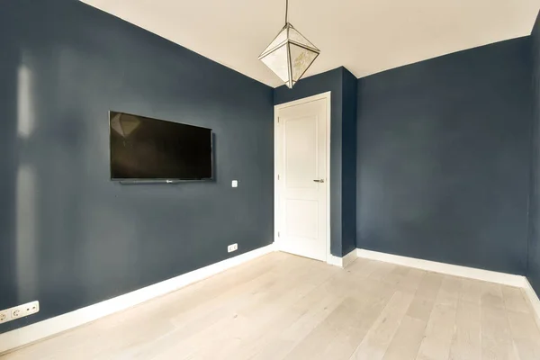 a living room with blue walls and white trim on the walls, there is a flat screen tv mounted in the wall