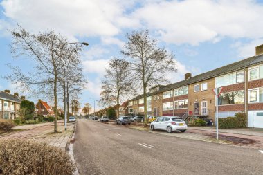 Boş bir cadde. Arabalar yan tarafta ve evler arka tarafta. Hepsi kameraya dönük.