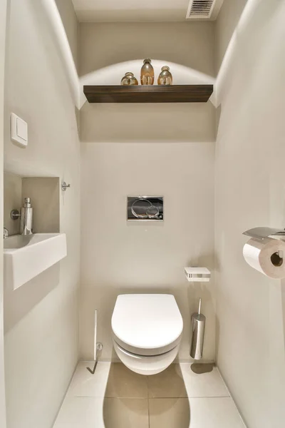 a toilet in the corner of a bathroom with shelves on the wall above it and an open window to the outside