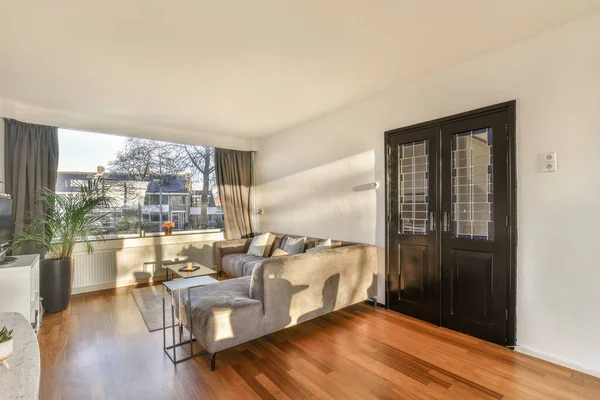 stock image a living room with wood flooring and white walls, there is an open door that leads to the patio