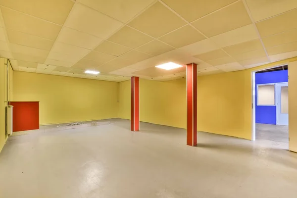房间里空荡荡的 墙壁是黄色的 天花板是白色的 墙角有一扇红色的门 — 图库照片
