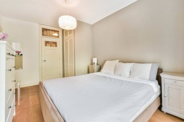 Odanın sağ köşesinde yatak odası, şifonyer ve ayna olan açık ahşap döşeme.