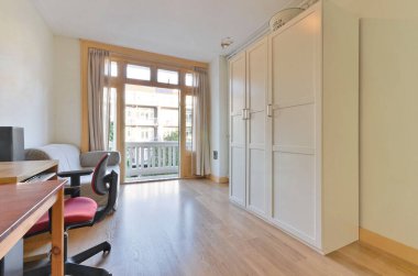 Kapısında masa, sandalye ve buzdolabı olan bir oda sağ tarafta açık.