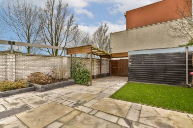 Güneşli, mavi bir gökyüzü gününde arka bahçesinde çitleri ve ağaçları olan bir arka bahçe.