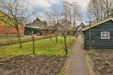 Arka planda ağaçlar ve ona giden boş bir yol olan yol kenarında küçük bir ev.