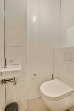 Duvarlarında beyaz fayanslar olan bir banyo ve yanında siyah bir tuvalet olan bir ayna.