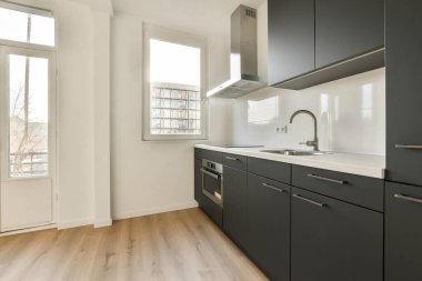 Lavabonun önündeki adada siyah dolapları ve beyaz tezgahı olan bir mutfak oturma odasına açıktır.