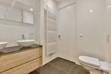 İki lavabosu ve lavabonun yanında tuvaleti olan modern bir banyo duvarda büyük bir ayna var.