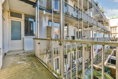 İkinci katta balkon ve balkon olan bir apartman kompleksi. Dışarıdan sokağa bakıyor.