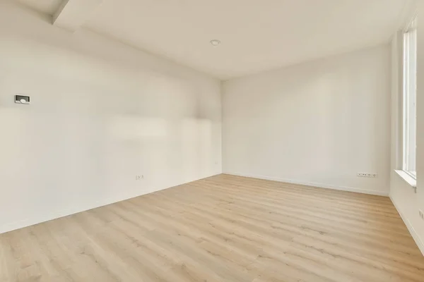 部屋の両側に白い壁と木の床がある空の部屋には大きな窓があります — ストック写真