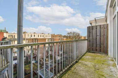 Arka planda binalar ve çitli bahçenin yanında büyüyen çimenler olan bir dış alan.