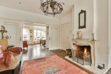 Şöminesinde şöminesi olan bir oturma odası ve yerde de kullanılmış bir halı.