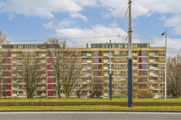 Een Appartementencomplex Met Rode Luiken Ramen Enkele Bomen Voorgrond Erachter — Stockfoto