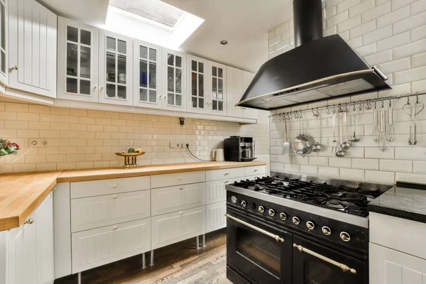 stock image a kitchen with white cabinets and wood counter tops on the stove hood above it is an image of a black range cooker