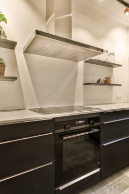 Bu fotoğraftaki tezgahlarda siyah dolapları ve paslanmaz çelik aletleri olan modern bir mutfak yukarıdan çekilmiştir.