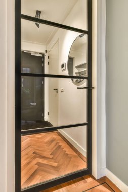 Duvarında büyük bir ayna ve önünde ahşap döşeme olan boş bir oda.