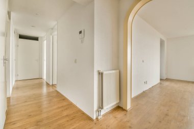 Odasında ahşap döşeme ve beyaz duvarlar olan boş bir oturma odası çok temiz, ama görmek zor.