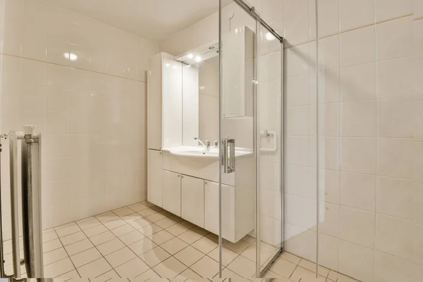 バスタブの横の角にシャワーストールとトイレのあるバスルームは床に白いタイルで — ストック写真