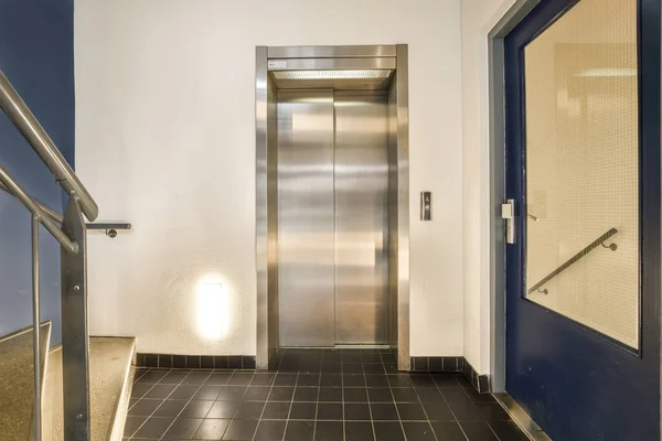 在有蓝色门和黑色瓷砖的大楼里的电梯 从前门可以看到 — 图库照片