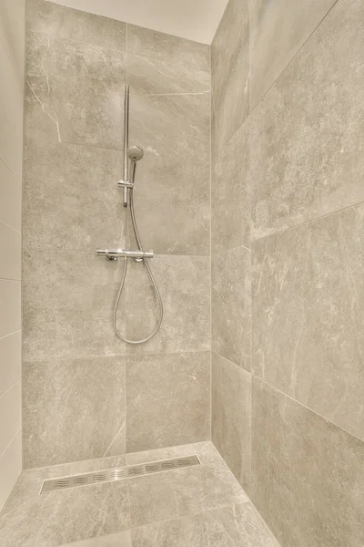 壁に大理石のタイルが敷き詰められた浴室のシャワーヘッドの周りの床は壁に取り付けられています — ストック写真