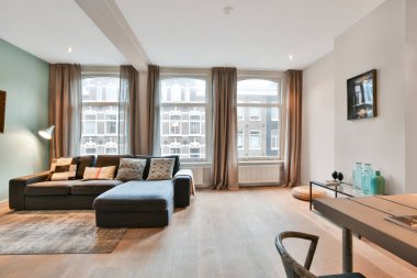 Kanepenin önündeki duvarda kanepe, masa ve televizyon olan bir oturma odası açık bir pencere.