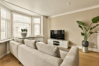 Odanın ortasında kanepeleri ve düz ekran televizyonu olan bir oturma odası duvarda.