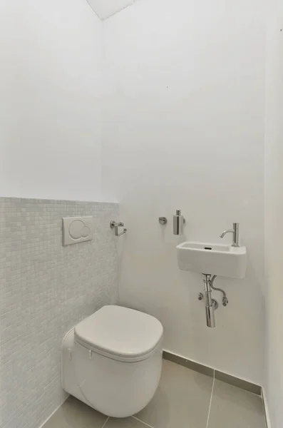 隅の壁とトイレに白いタイルのバスルームシンクの上に鏡があります — ストック写真