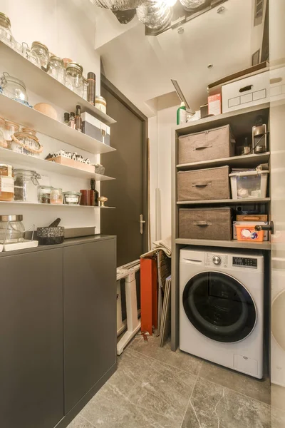a laundry room with a washer, dryer and other items on the shelfs in front of the washer